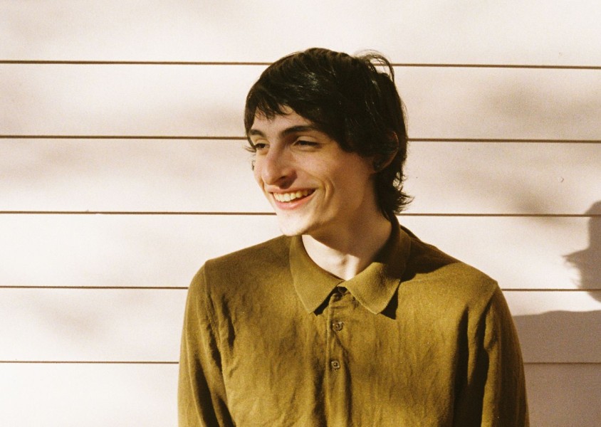 Boy smiling in green shirt against wallx